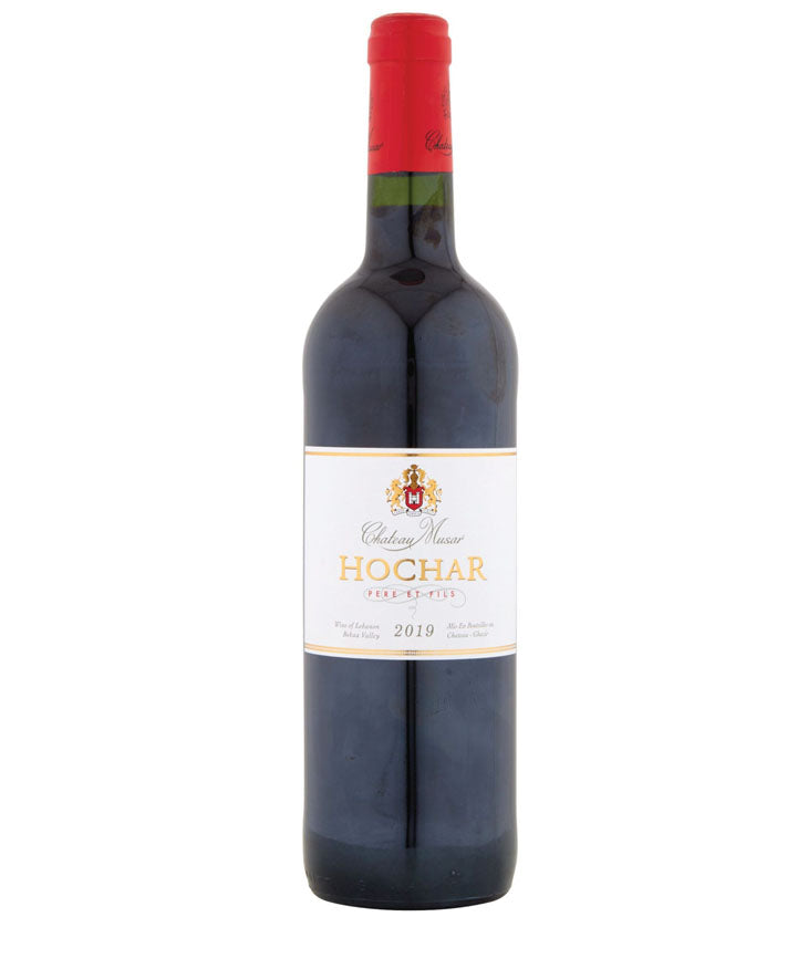 A bottle of Chateau Musar Hochar Père et Fils 2019 red wine. The bottle has a red foil capsule and a white label with gold and black text. The label features a crest at the top, the name 'Chateau Musar' in cursive, 'HOCHAR' in bold gold letters, and 'Père et Fils' beneath in red. The wine is from the Bekaa Valley in Lebanon.